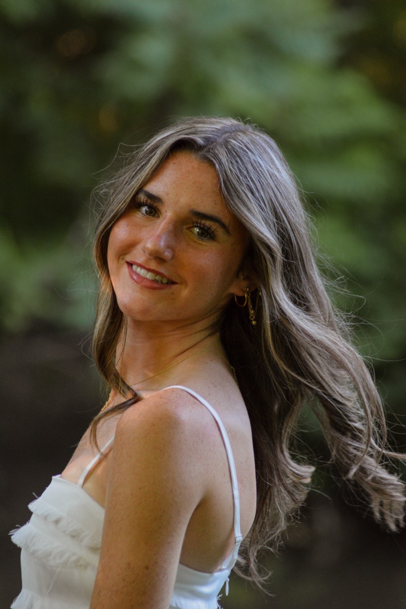A smiling outdoor portrait with a soft green background
